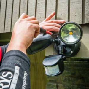 Hamilton Electrician installing exterior motion sensor light on weatherboard home